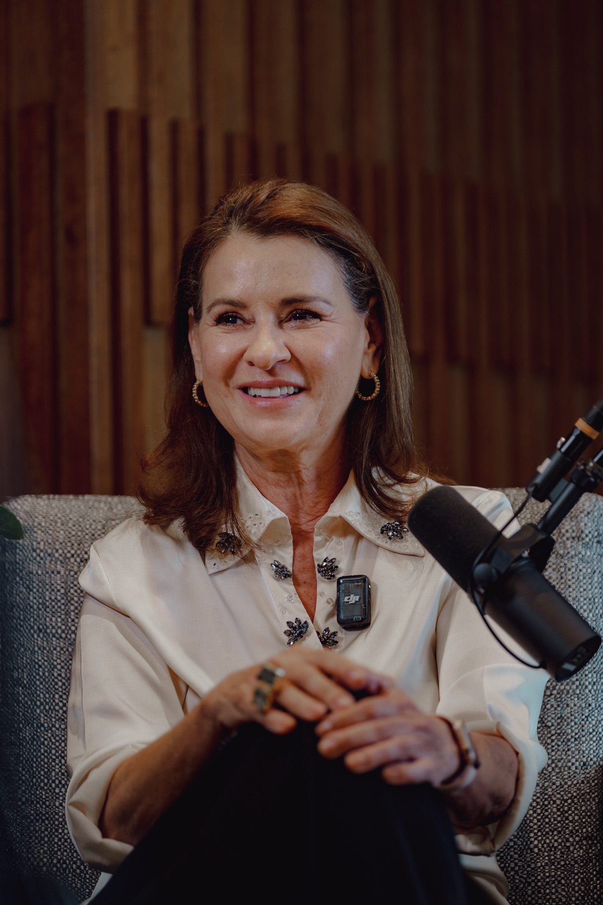 Invitada sonriendo frente al micrófono durante una grabación de podcast